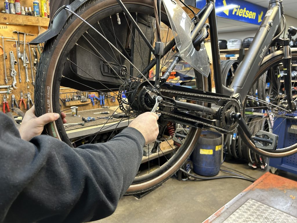 Monteur repareert een fiets in de werkplaats van RG Tweewielers